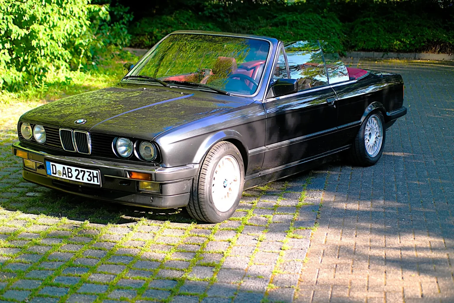 BMW E30 325i steht seitlich auf einem Parkplatz im grünen Düsseldorf