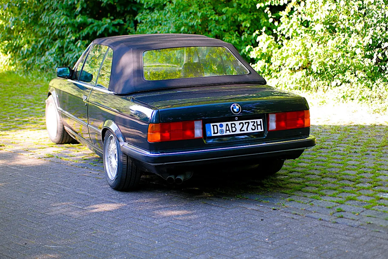 BMW E30 steht mit dem Heck zu sehen, vor einem Baum
